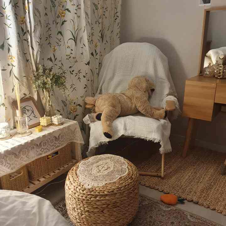 ベージュとブラウンの落ち着いた寝室の一角、ホワイトのアームチェアとラタンの小物が配置されたナチュラルな雰囲気のインテリア