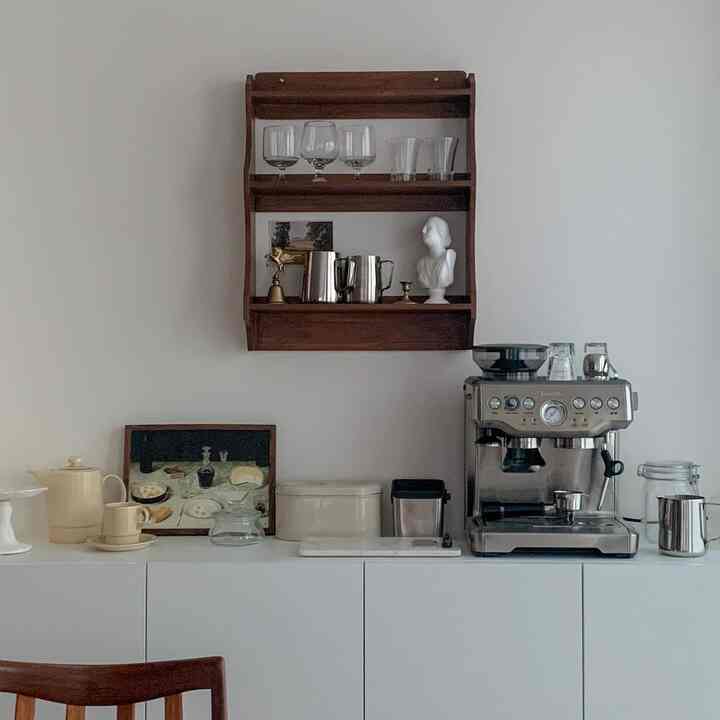 ホワイトとシルバーが調和したシンプルモダンなおうちカフェ空間、木の棚とコーヒーマシン、多彩なカップが整然と配置されている