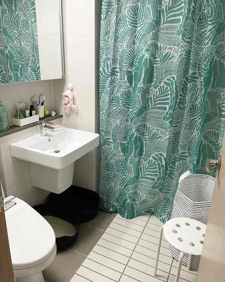 White and green toned small bathroom featuring a sink, toilet, cat litter box and a stool in a clean layout