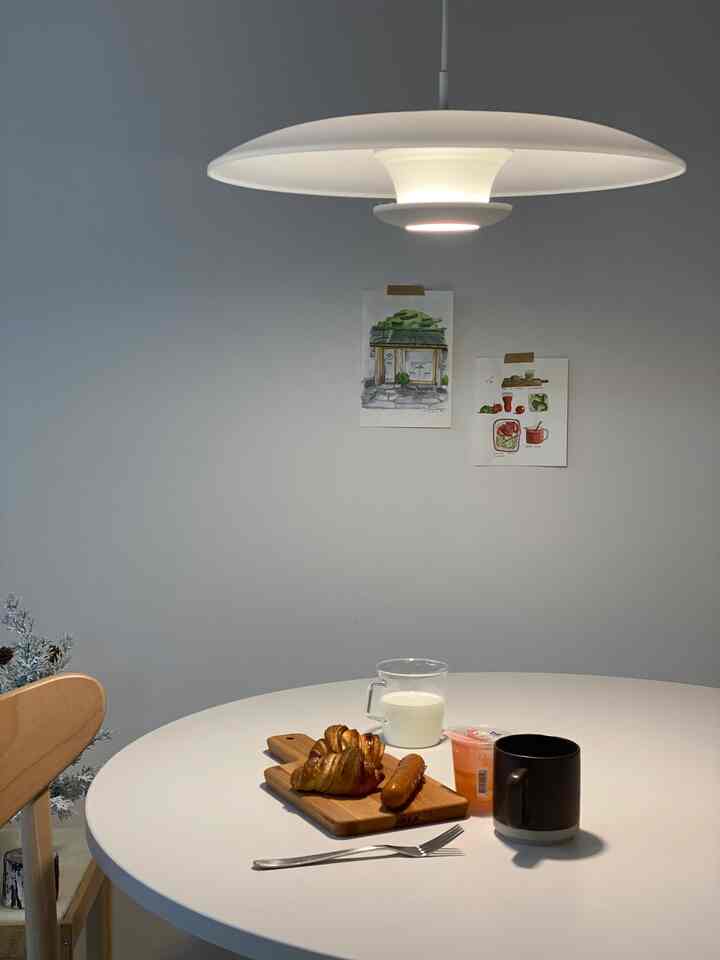 White-toned round dining room featuring a white round table and wooden chair, creating a simple and natural ambiance