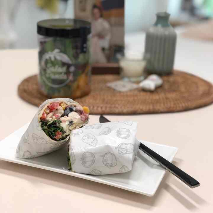 White-toned dining table featuring wrapped sandwich and fork in a clean cafe-style setting