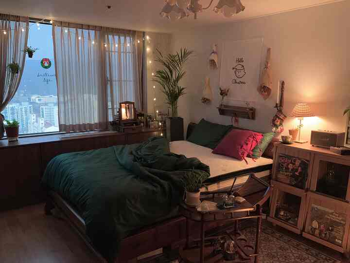Cozy vintage bedroom with dark green bedding, warm string lights and curtains creating a Christmas atmosphere
