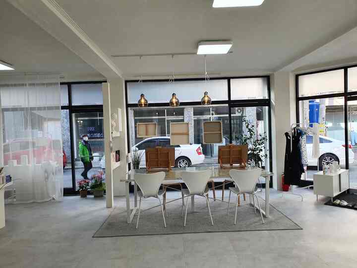 Bright and spacious cafe-style interior in white and gray tones, featuring a large dining table and white chairs centrally arranged
