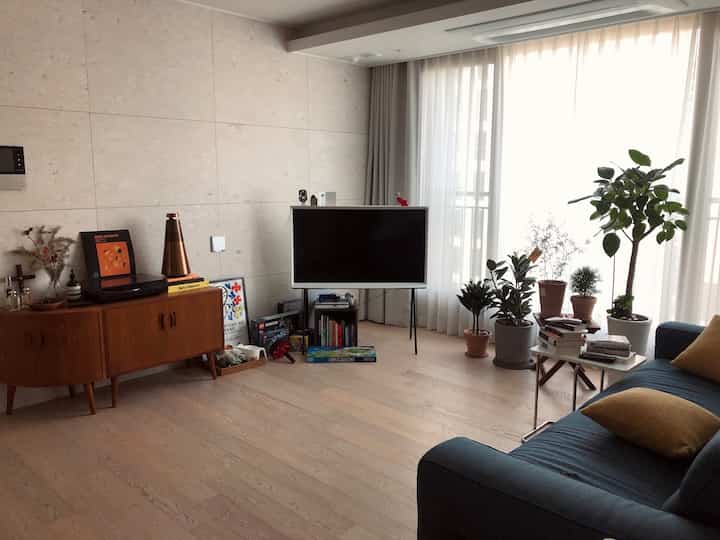 Natural and white toned living room featuring vintage furniture, plants, and a modern bright atmosphere.
