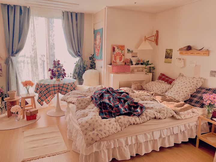 白とウッドトーンが調和した寝室、クリスマスツリーとチェッカーテーブルクロスが配置された雰囲気のあるインテリア