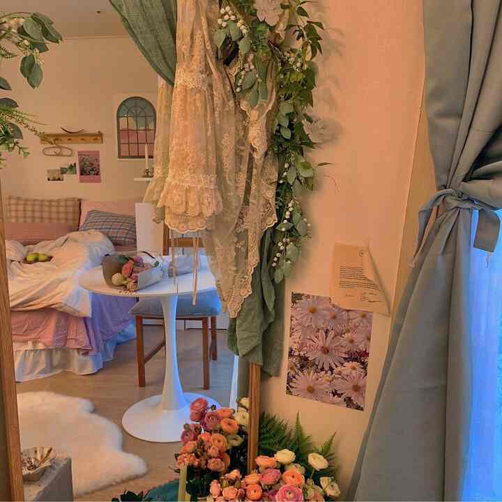 Natural-toned bedroom with white and green accents, featuring a full-length mirror, natural furniture, and flower bouquets creating a cozy atmosphere