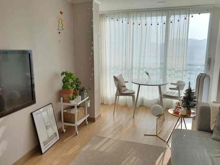 A white and natural-toned living room featuring a mini Christmas tree, mobile, and garland, creating a cozy Christmas mood
