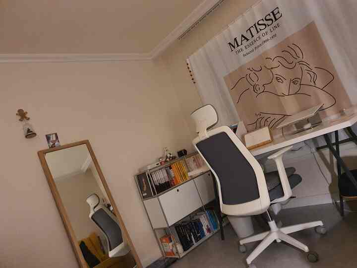 A white and beige toned home office featuring a wooden full-length mirror and Henri Matisse poster creating a neat workspace