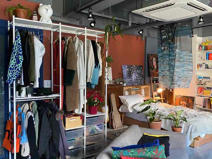 Natural modern bedroom featuring a closet rack, bookshelf, and sofa with cozy atmosphere