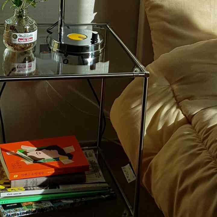 Natural beige-toned bedroom space featuring a cushioned sofa and chrome frame side table with cozy atmosphere