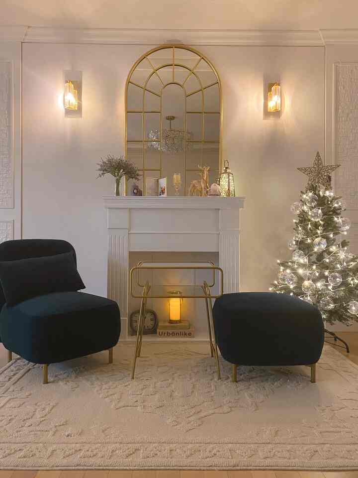 White and gold toned living room featuring a fireplace and Christmas tree, creating a modern, warm atmosphere