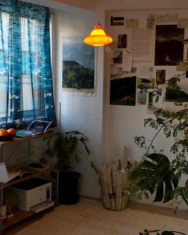 Natural modern home office space featuring blue curtains and vintage posters with warm pendant lighting accent