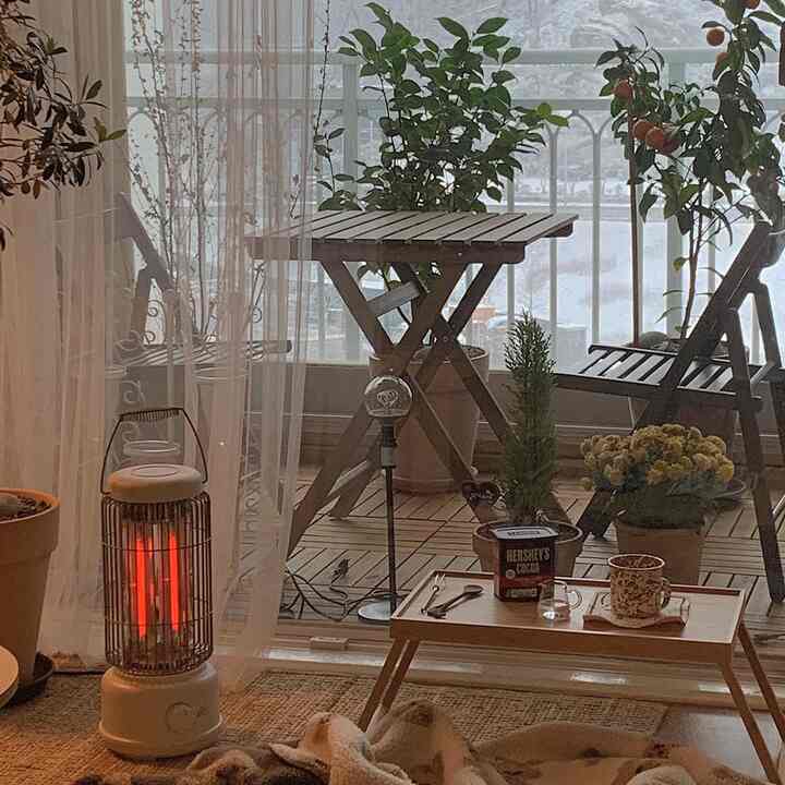 ナチュラルな木目調のベランダ空間、木製家具と暖かい電気ヒーター、居心地の良いおうちカフェの雰囲気