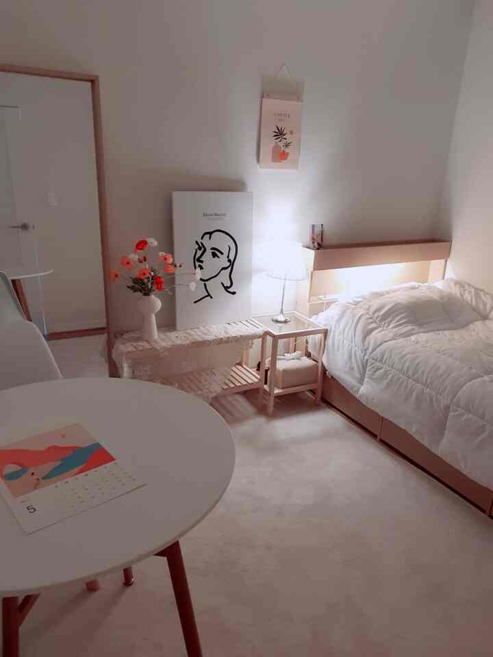 柔らかいホワイトとウッドトーンが調和する居心地の良い寝室、整ったベッドとナイトテーブルにやわらかな照明が灯る空間