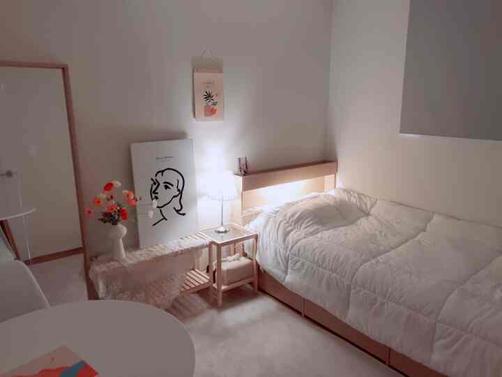 白と木目調が調和した一人寝室、快適なベッドとナイトテーブルが配置されたナチュラルモダンなインテリア