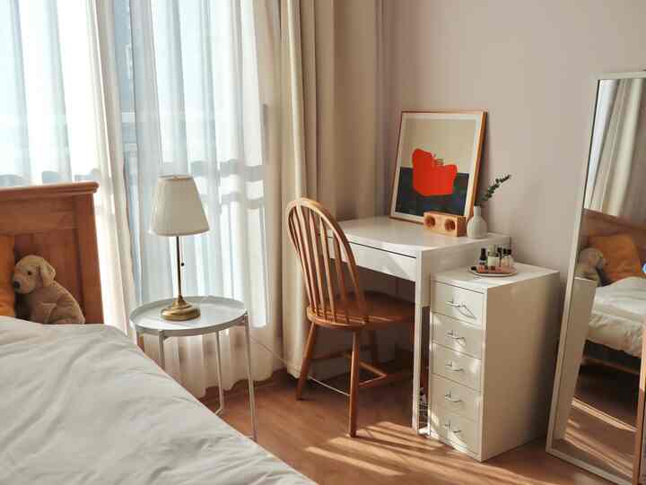 White and wood tone bedroom featuring a simple, natural desk and chair creating a cozy space