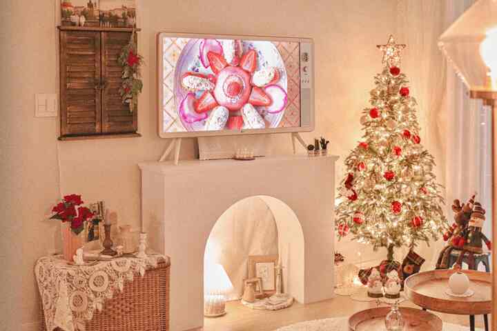 温かみのあるホワイトとレッドの色調のリビング、暖炉やヴィンテージのサイドテーブル、飾られたクリスマスツリーが調和した雰囲気のあるインテリア。