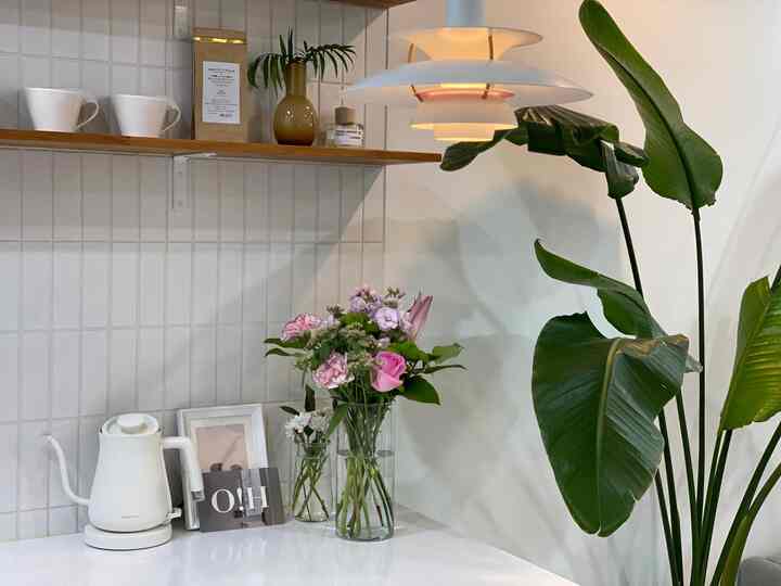White and green toned kitchen featuring vases and coffee kettle with a clean and simple interior