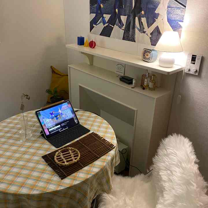 Natural-toned studio bedroom with a round table featuring a checkered tablecloth and rattan accents, warmly lit cozy interior