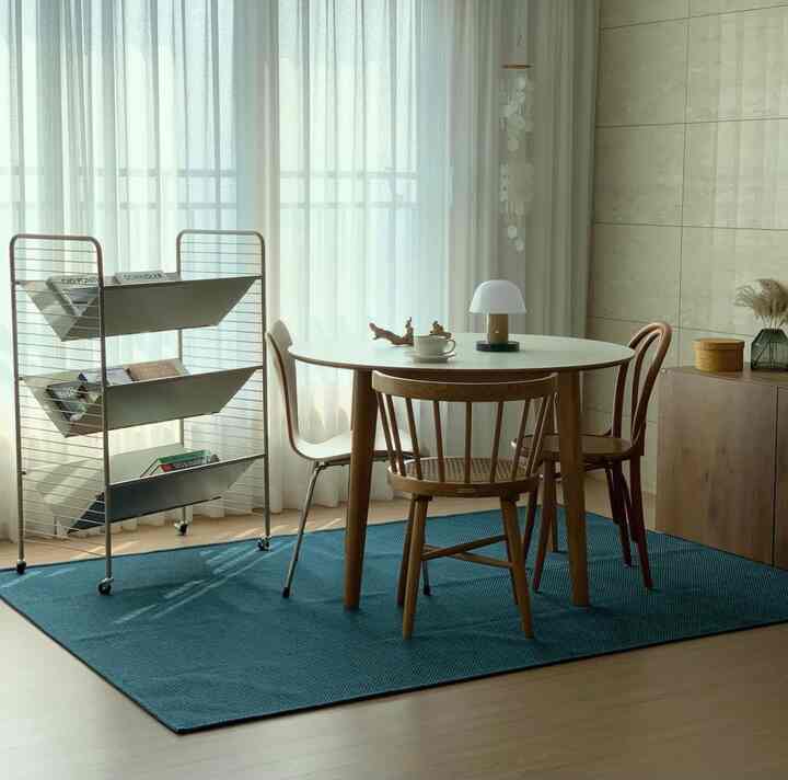 Bright living room workspace with natural modern vibe featuring white and wood tones, round table and chairs near window