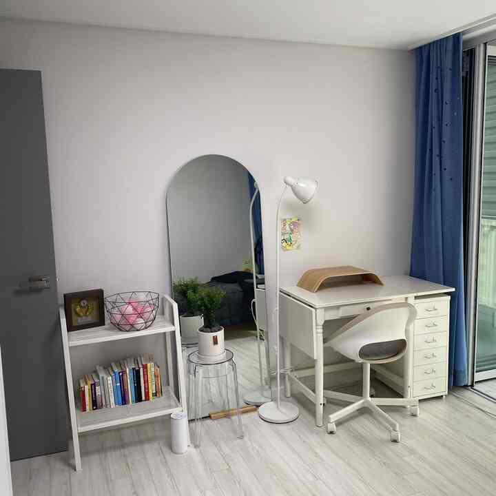 ホワイトとブルーのトーンの大学生の部屋、シンプルなホワイトデスクとゴーストスツール、アーチ型全身鏡が配置された実用的な勉強スペース