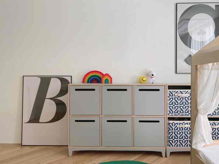 Natural toned kids' room featuring toy storage cabinet and wood tone furniture in a cozy space