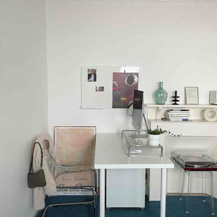 白と透明素材の調和したコンパクトなホームオフィス空間、デスク、透明チェア、額縁、ターンテーブルが配置されたミニマルなインテリア