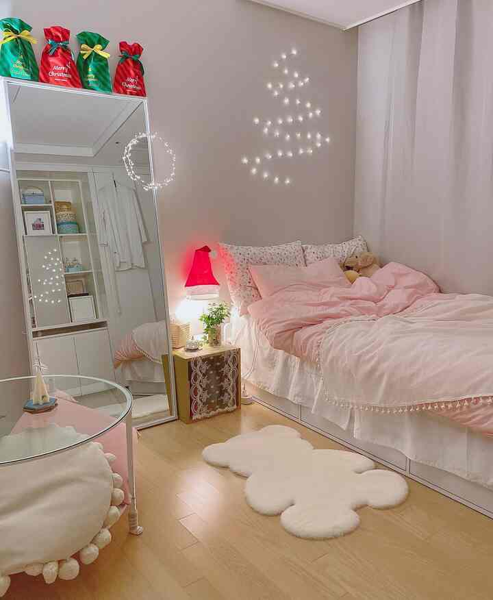 Pink-toned studio bedroom featuring a bear-shaped rug, Santa hat lamp, and festive Christmas decorations creating a cozy holiday atmosphere