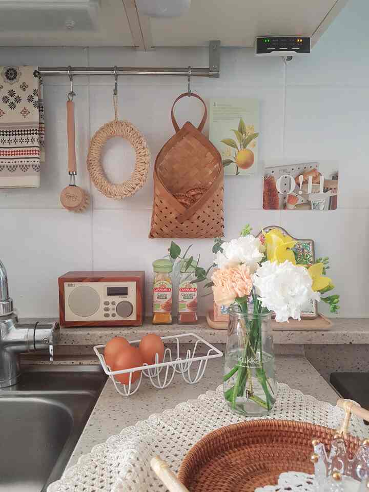 White and beige toned kitchen space featuring rattan accessories and a flower vase arranged naturally for a cozy kitchen interior