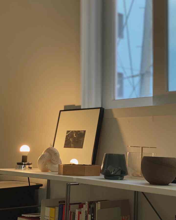 Warmly lit white-toned home office workspace featuring wood tone objets and bookshelf with a clean, organized atmosphere