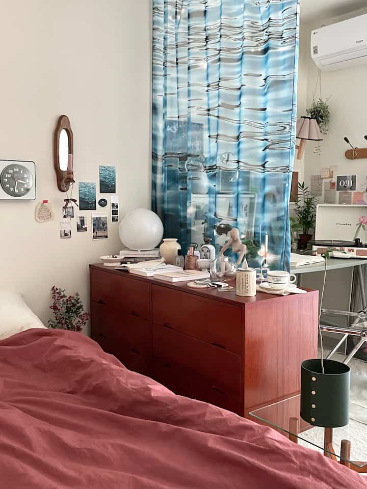Natural-toned bedroom featuring a wooden dresser and blue curtains with a cozy atmosphere