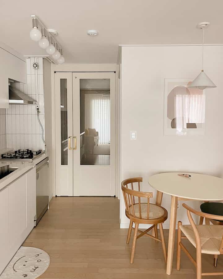 アイボリーと木目調が特徴のキッチンとダイニングスペース、清潔で温かみのあるカフェ風インテリア