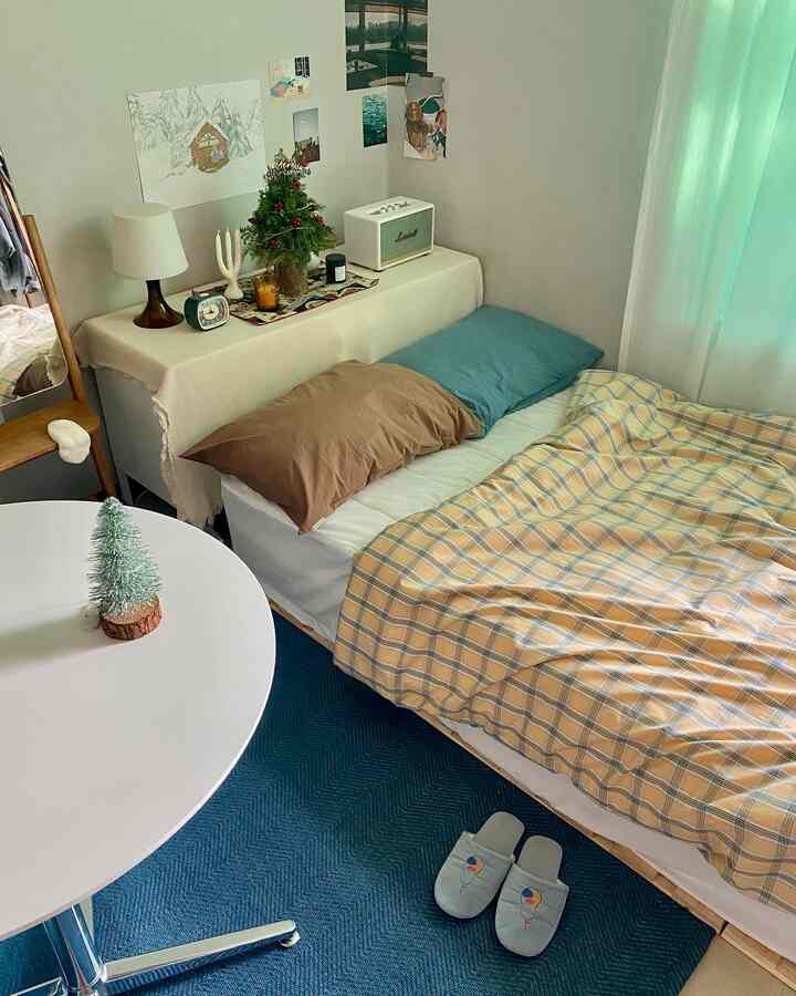 白と青の色調のワンルーム寝室、チェック柄の寝具とクリスマス装飾が配置された居心地の良い空間