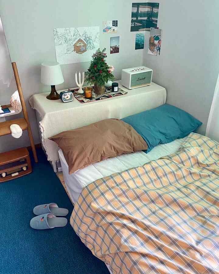 ブルーとブラウンのトーンのワンルーム寝室、チェック柄の掛け布団カバーと枕が配置された雰囲気のある空間