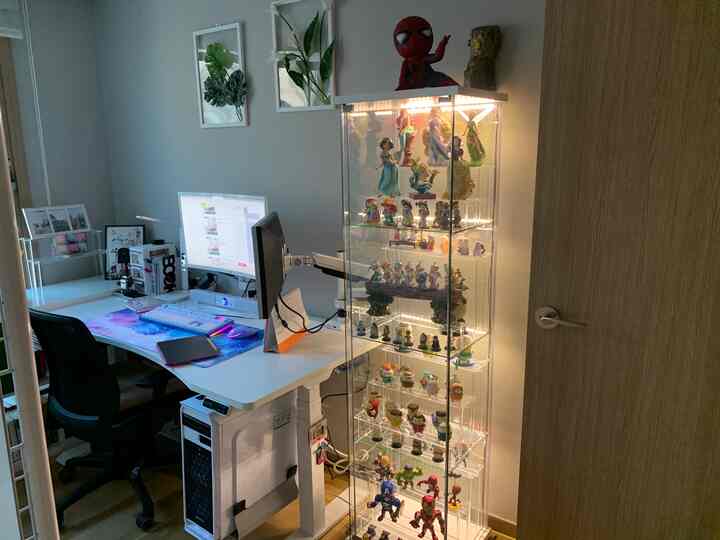 White and transparent toned home office featuring desk, office chair, and illuminated glass display cabinet in a tidy workspace