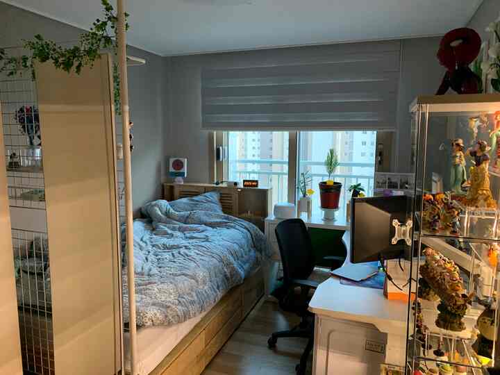 A cozy 6-tatami size bedroom in white and wood tones featuring a bed, desk, and office chair in a compact studio apartment