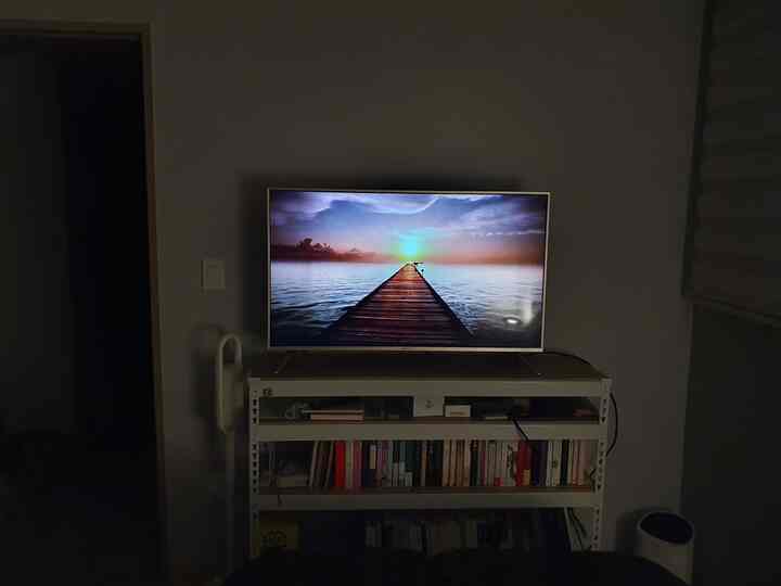 薄暗い照明の中、白いラックの上に置かれたLEDテレビのあるリビングスペース