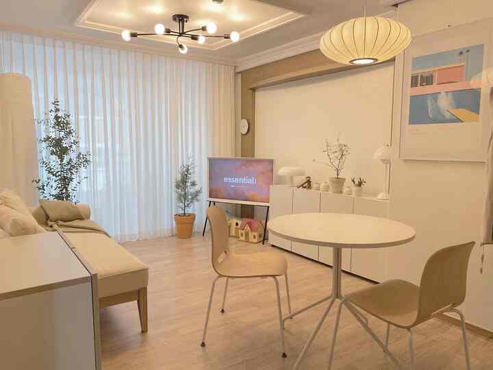 White and wood-tone hotel-like living room featuring a round dining table and simple sofa in a clean, minimalist setting