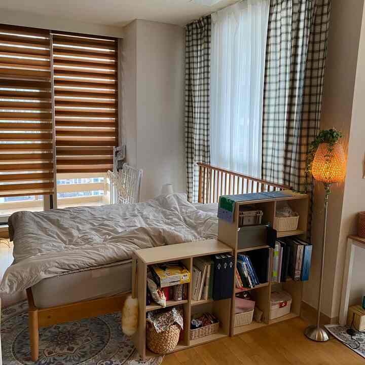 White and wood-toned bedroom featuring bed and bookshelf, creating a cozy and natural atmosphere