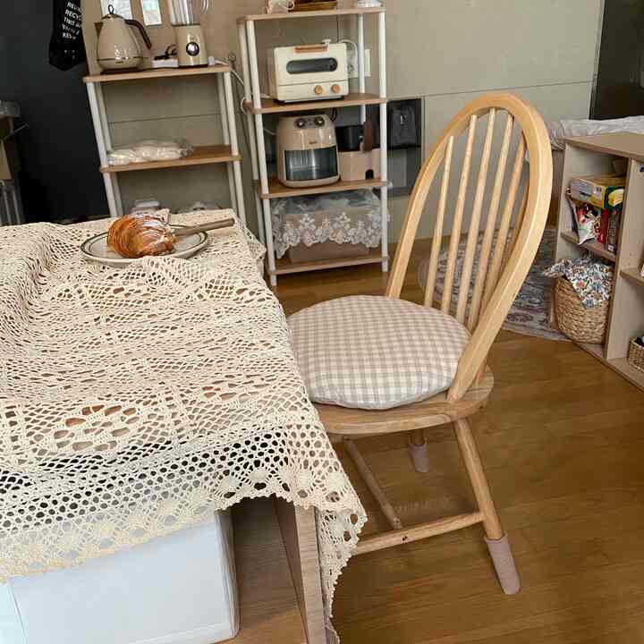 Beige and wood tone kitchen dining area featuring a wooden chair and crocheted tablecloth, creating a cozy natural interior