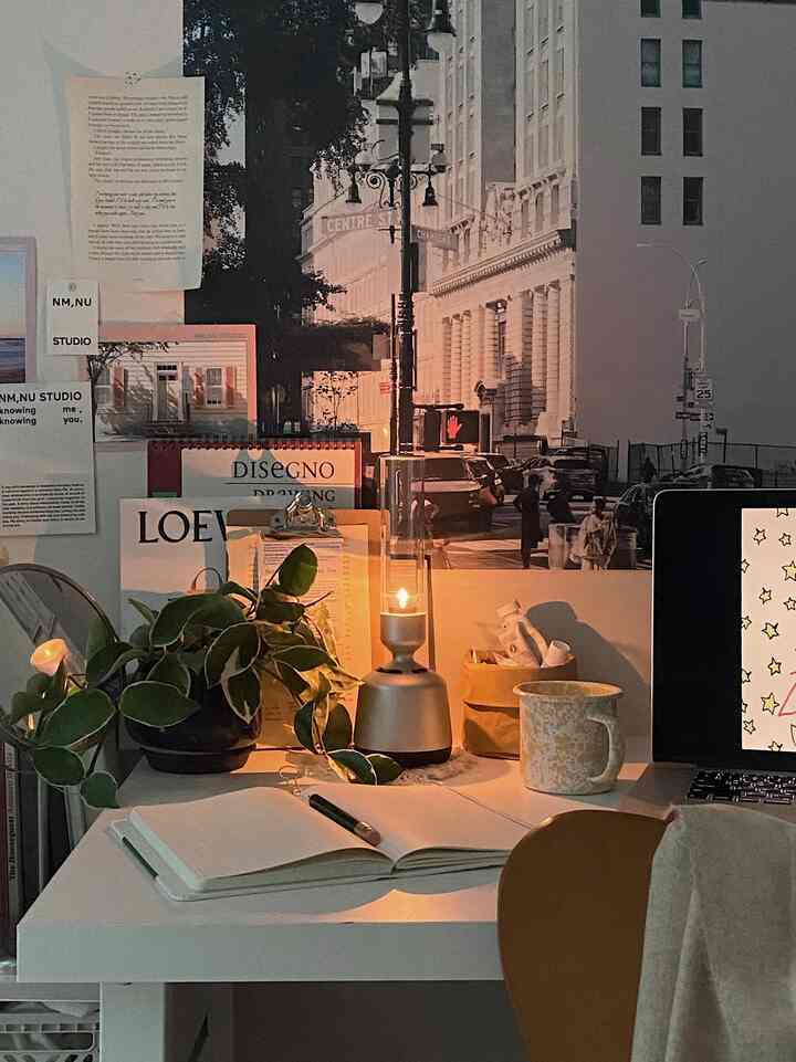 Warm brown and white toned home office space with desk featuring table lamp and plant creating a cozy atmosphere
