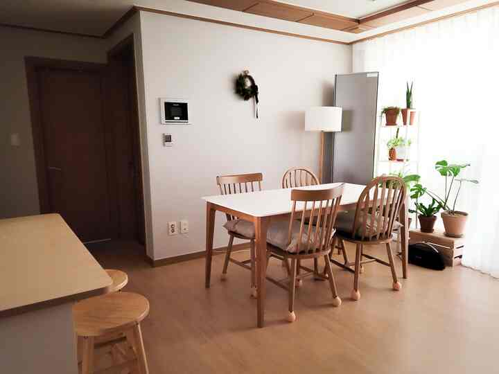 Natural wood tone and beige dining room featuring plants and bar stools with a cozy atmosphere