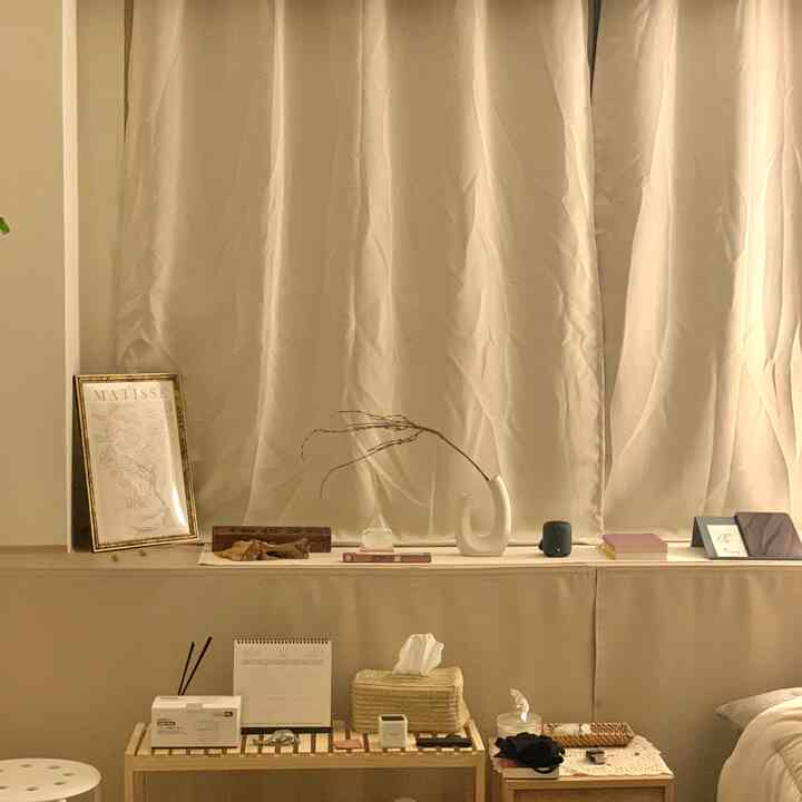 Cozy space in ivory and beige tones featuring wooden shelves, rattan accessories, and a Henri Matisse poster by the window