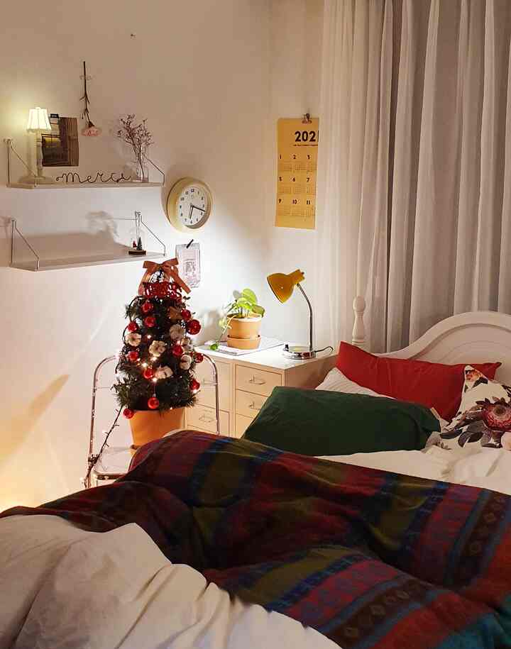 Warm white-toned bedroom with cozy red and green Christmas tree decorations