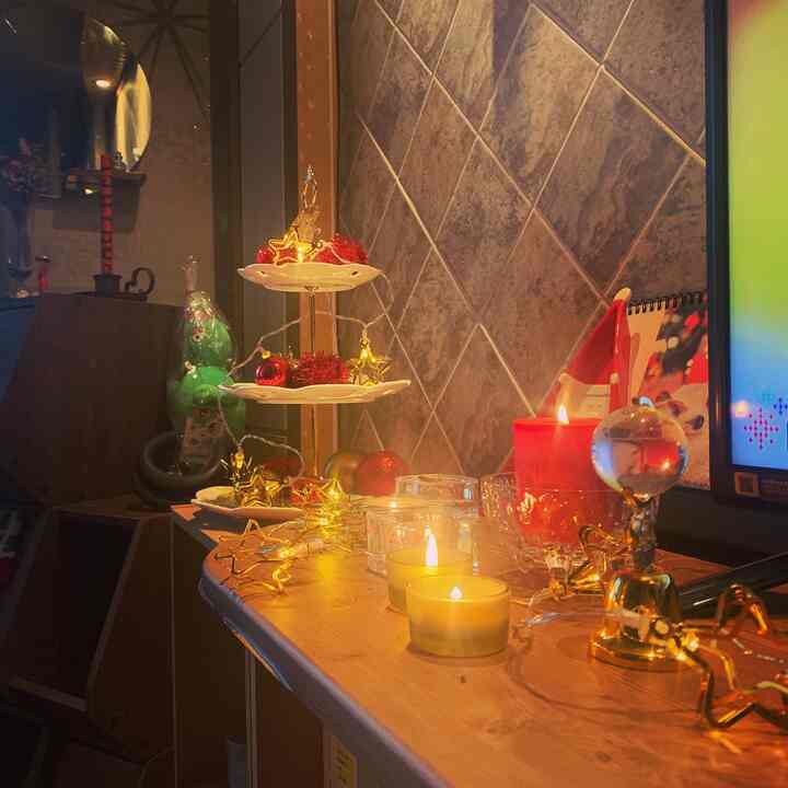 Cozy space featuring warm gold and red Christmas decorations with a tiered tray and lit candles