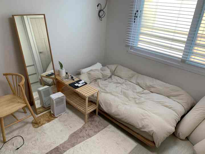 White and wood tone small bedroom featuring a simple wooden shelf and window blinds with cozy atmosphere