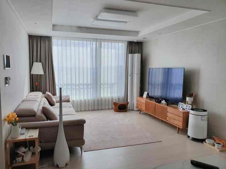 Natural toned living room featuring light beige sofa, wood-toned TV stand, and a bright rug creating a cozy atmosphere