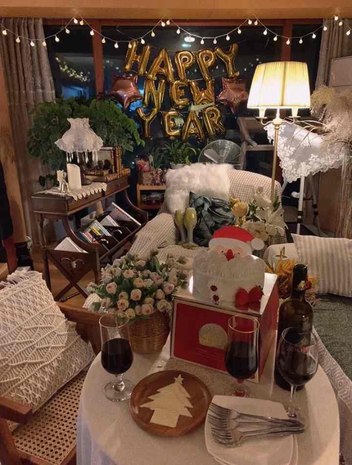 Cozy natural-toned living room decorated for Christmas, featuring a home party table, lighting, and vintage furniture ambiance