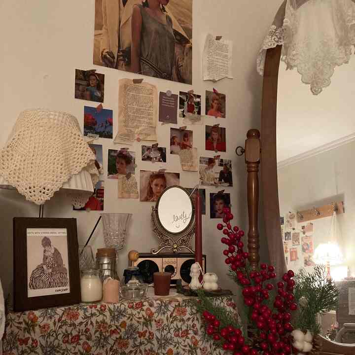 白い壁と茶色い木製の鏡があるヴィンテージ感覚の空間。花柄ファブリックやキャンドル、ハンドメイド風の小物が配置された温かみのあるインテリア。