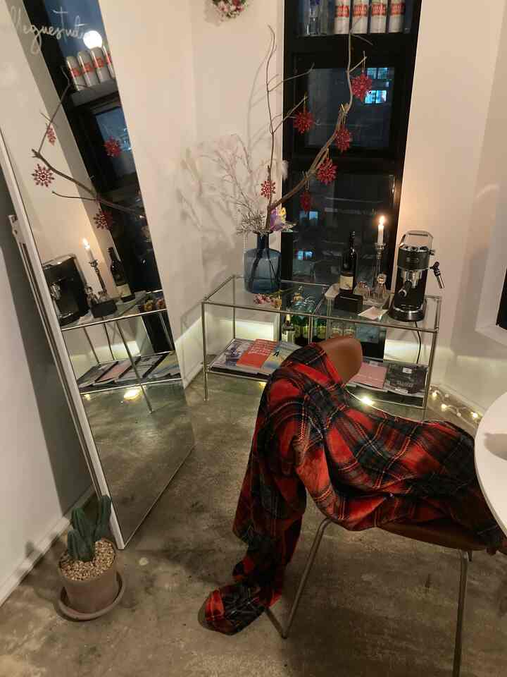 White and brown toned design workspace featuring a glass console, coffee machine, and red plaid blanket creating a cozy atmosphere